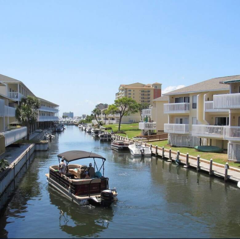 Pontoon boat cruising the calm canal between condo buildings at Sandpiper Cove